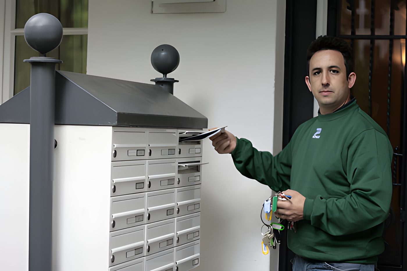 Hausmeister mit Schlüsselbund an der Briefkastenanlage eines Hauseingangs
